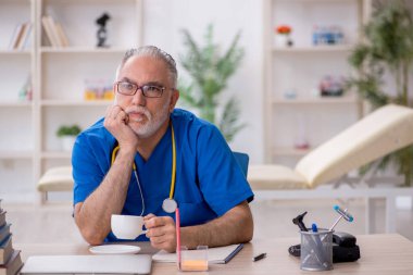 Yaşlı doktor molada kahve içiyor.