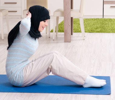 Tesettürlü genç kadın evde egzersiz yapıyor.