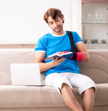 Kolu yaralı genç adam kanepede oturuyor.