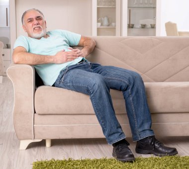 Beyaz sakallı yaşlı adam evde acı çekiyor.