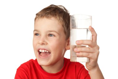 Küçük çocuk gülüyor ve bardağını suyla tutuyor.