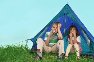 Küçük çocuklar doğada dinlenir, çadırın yanına oturur ve tatlı yerler..
