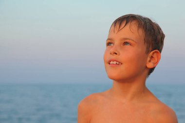 Yüzdükten sonra küçük çocuğun başı deniz kıyısında. Saçları ıslak.