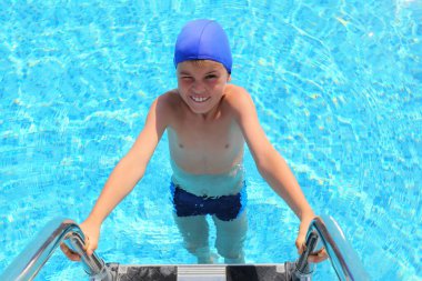 Koyu mavi şapkalı ve eriyen bir çocuk havuza giriyor.