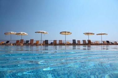 Açık plaj şemsiyeleri ve su altı paketleriyle çit kenarındaki iskemlelerin yanında.