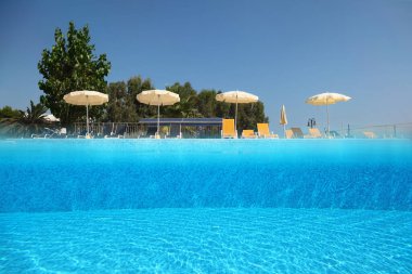 Açık gökyüzünün altındaki havuz. Güverte sandalyelerinin şemsiyelerle durduğu yer. Su altı fotoğrafı.