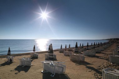 Şafak vakti kumsalda şemsiyeli güneşlik yapılır.