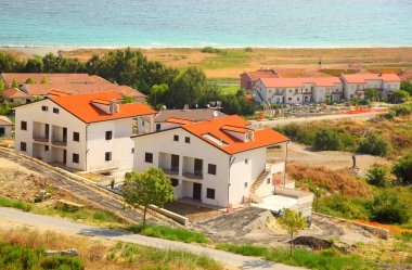 Kumsalda kahverengi çatıları olan iki katlı yeni beyaz evler inşa ediliyor.