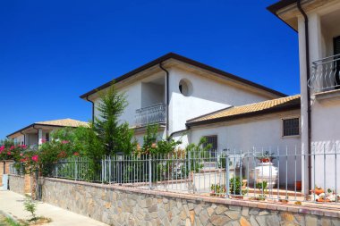 Güneşli bir günde bahçeli ve balkonlu beyaz iki katlı kır evleri.