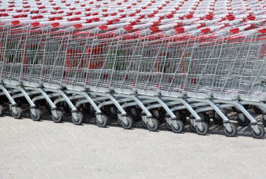 Dışarıda kırmızı saplı süpermarket arabaları var.