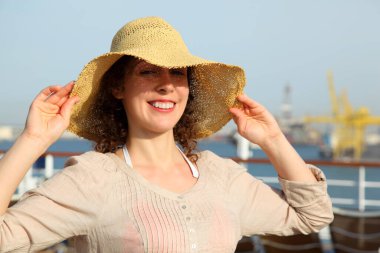 Güzel, gülümseyen kız, yolcu gemisinin güvertesinde saman deniyor.