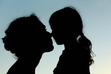 Burunlara, yan görüntülere, gökyüzüne dokunan anne ve kızın silueti.