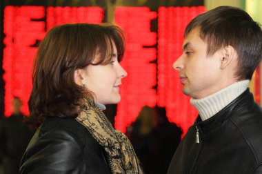 Deri ceketli kadın ve erkeğin profili uçuş takviminin arka planında göz göze bakın.