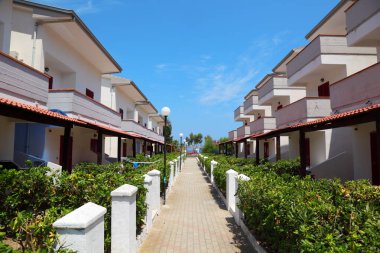 Sahildeki tatil köyü manzarası. Üç katlı balkonlu villalar.