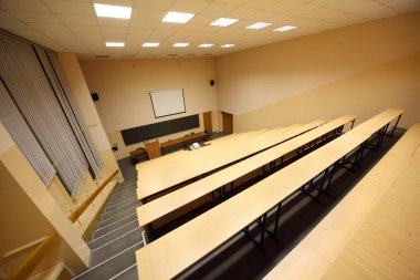 Sınıflar, üniversite konferans salonu, büyük tahtalar, tahta masalar ve banklar.