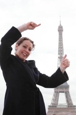 Gülümseyen genç kadın, Eyfel Kulesi 'nin ne kadar yüksek olduğunu elleriyle gösteriyor..