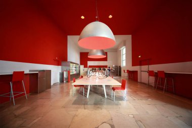 Küçük, rahat bir kafedeki insanlar. Beyaz masalar, kırmızı sandalyeler ve duvarlar