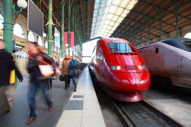 İnsanlar Perron 'a, kırmızı ve gri yolcu trenlerine Paris, Fransa' daki tren istasyonuna gidiyor.