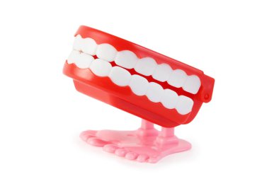 side view of bright toy clockwork jaw with white teeth on pink legs on white background clipart