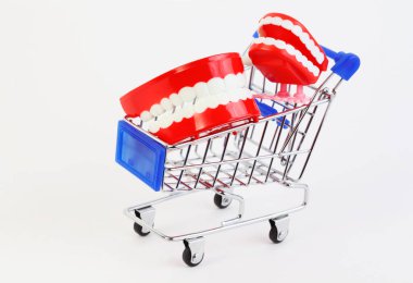 two small toys jaw with white teeth in purchasing cart on white background clipart