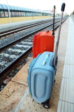 Tren raylarının yanındaki platformda iki büyük seyahat çantası duruyor. perspektif