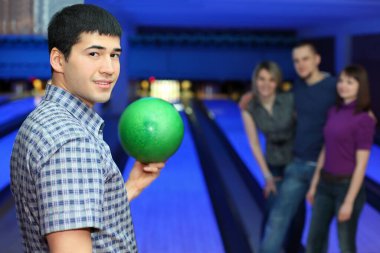 One fellow stands sideways and holds ball for playing in bowling and three friends hearten him, focus on  man clipart