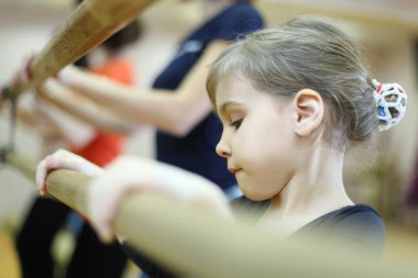 concentrated face of little girl in ballet class near frame and large mirror clipart