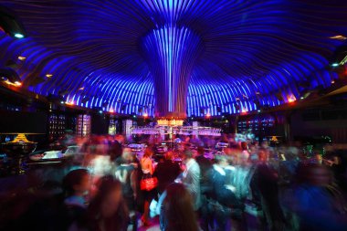 Bir grup insan gece kulübünde rahatlıyor, içiyor ve dans ediyor.