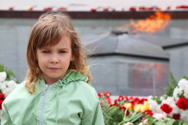 beautiful little girl stands near memorial, eternal flame, flowers clipart