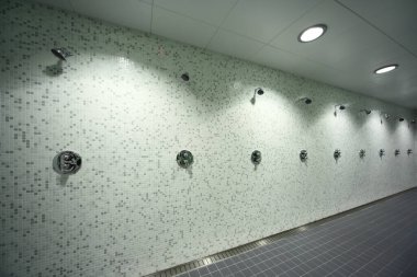 Büyük, hafif, boş umumi duş odası, duvarlarda yeşil fayans, gri zemin