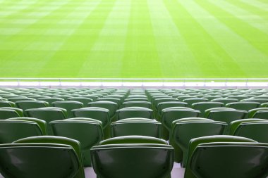 Rows of folded, green, plastic seats in very big, empty stadium clipart