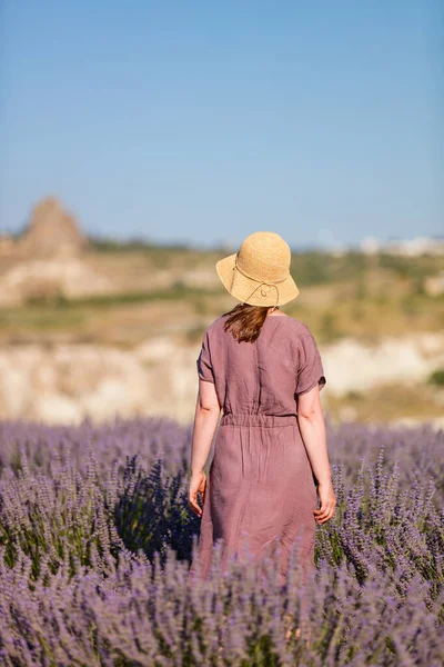 Young woman in lavender flowers field wearing purple dress.