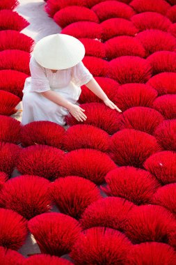 Vietnam 'da Hanoi yakınlarındaki bir köyde pembe tütsü çubukları arasında konik şapka takan turist kadınların en iyi görüntüsü.