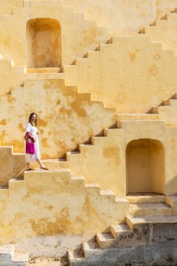 Woman walking down stairs at ancient stepwell in Jaipur India clipart