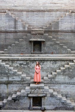 Woman walking down stairs at ancient stepwell in Jaipur India clipart