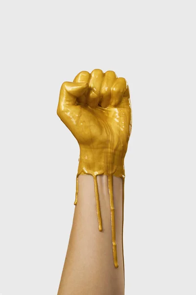 The hand is in gold acrylic paint, the paint covers the hand like a latex glove.
