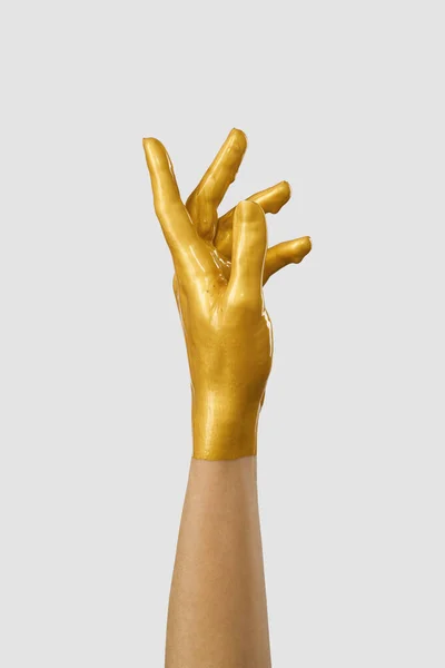 The hand is in gold acrylic paint, the paint covers the hand like a latex glove.