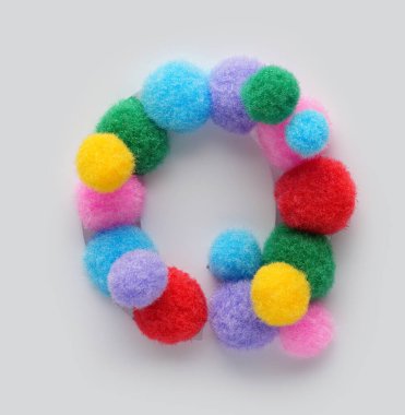 Beyaz arka planda tüylü ponponlardan yapılmış renkli Q harfi. Alfabe, eğitim tasarımı, oyuncu sınıf dekorasyonu ve grafik projeleri öğrenen çocuklar için yaratıcı el yapımı tipografi.