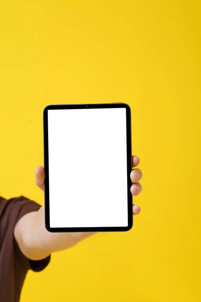 close-up image of a mans hand holding a blank screen Tablet PC against a yellow background, showcasing technology concept and digital revolution. Copy Space concept for advertising. . High quality