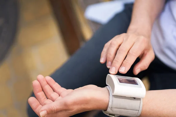 stock image Close-up of elderly womans hands holding pressure measurement device outdoors. The image portrays the concept of health monitoring, diagnosis, and healthcare for seniors. High quality photo