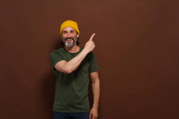 Pria Kaukasia Yang Tersenyum Dengan Topi Kuning Menunjuk Tangannya Samping — Stok Foto