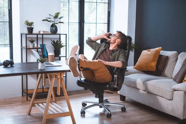 사업가는 사무실에서 휴식을 취하고 자세를 취하면서 전화로 대화를 나눈다 이미지는 — 스톡 사진