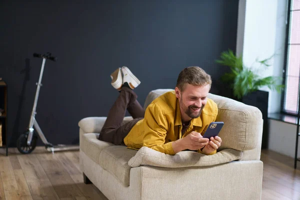 Homme Souriant Appréciant Temps Maison Assis Sur Canapé Avec Téléphone — Photo
