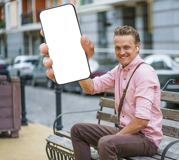 Чоловік Сидить Міській Лавці Тримаючи Мобільний Телефон Білим Екраном Який — стокове фото