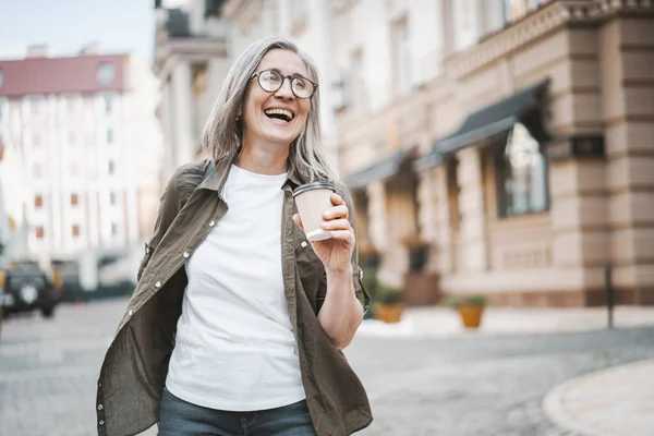 Şehirde Yürüyen Bir Fincan Kahvenin Keyfini Çıkaran Gümüş Saçlı Olgun — Stok fotoğraf