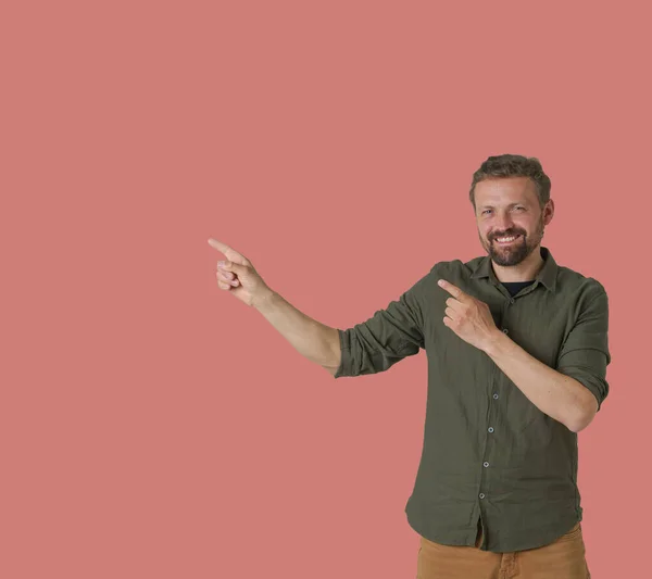 男はピンクの背景に描かれ 手でダイナミックで表現力豊かなジェスチャーを紹介しています 彼は矢印を示すために彼の手を使用して 方向や動きの感覚を示します 高品質の写真 — ストック写真