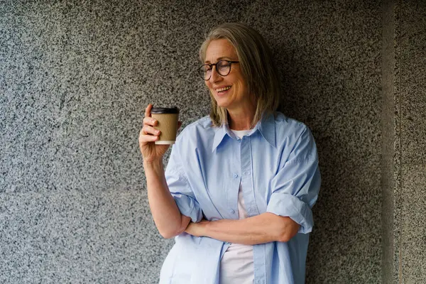 Een Vrouw Met Een Bril Staat Met Een Kop Koffie Rechtenvrije Stockafbeeldingen