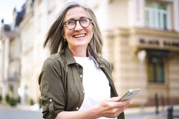Μια Γυναίκα Γυαλιά Κρατάει Ένα Κινητό Στο Χέρι Της Εικόνα Αρχείου
