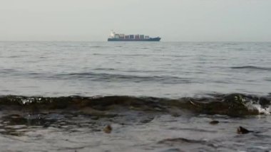 Cargo ship on sea horizon. Shot with copyspace and waves on foreground.