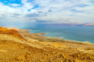 İsrail. Doğanın en büyük harikası Ölü Deniz 'dir. Bulutlu ve açık Ocak günü. Deniz yüzeyi bulutları yansıtır. Denizin karşı kıyısındaki Ürdün loş kış güneşiyle aydınlanır.. 